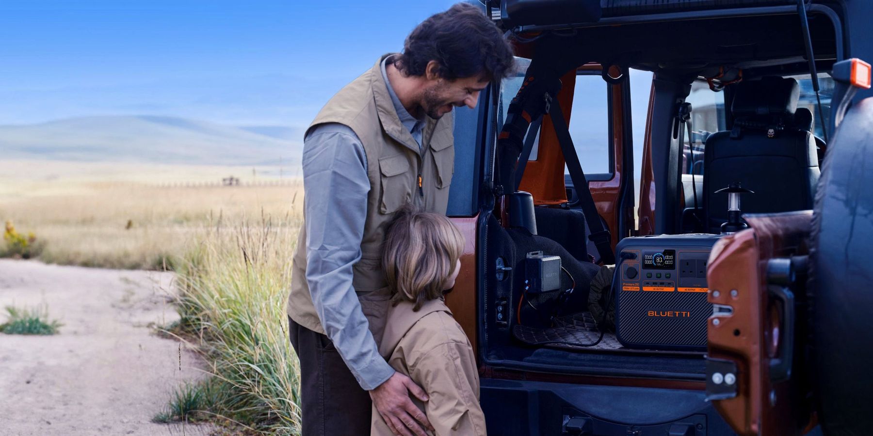 Father and child at an open 4x4 tailgate, Premium 200 V2 and BLUETTI Charger 1 in the boot